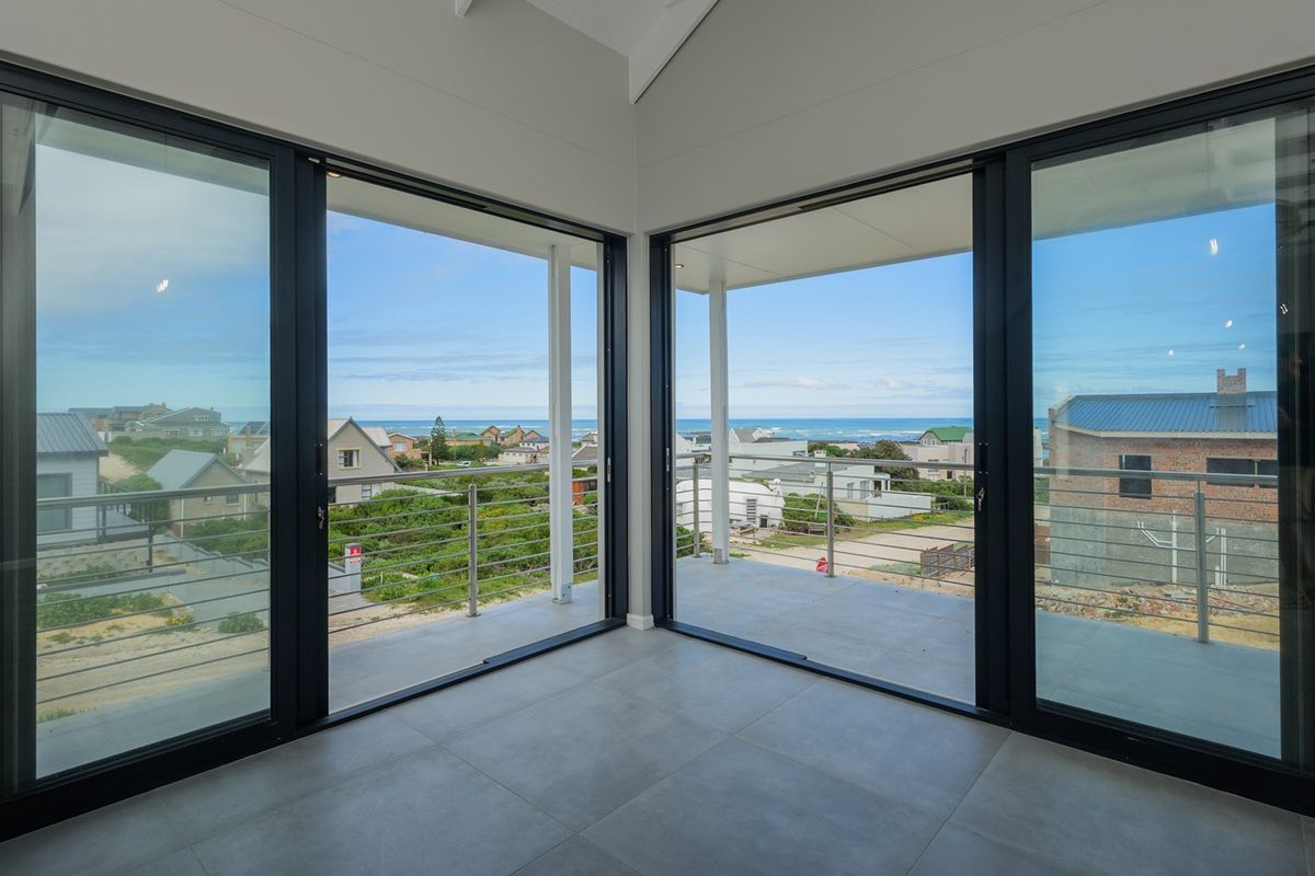 Bright, modern living area featuring expansive sliding glass doors that open onto a covered balcony with scenic coastal views.