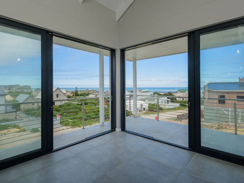 Bright, modern living area featuring expansive sliding glass doors that open onto a covered balcony with scenic coastal views.