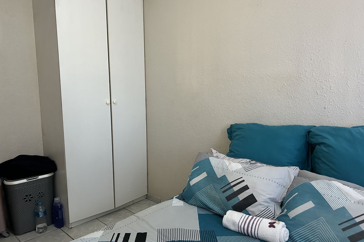 A bedroom featuring tiled flooring and a built-in wardrobe with white doors.