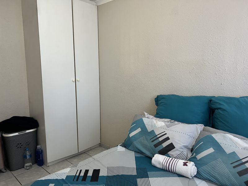 A bedroom featuring tiled flooring and a built-in wardrobe with white doors.