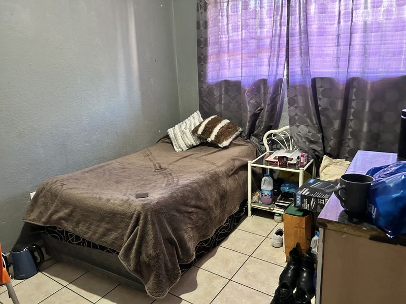 A compact bedroom featuring tiled flooring and painted walls, currently utilized as a sleeping space.