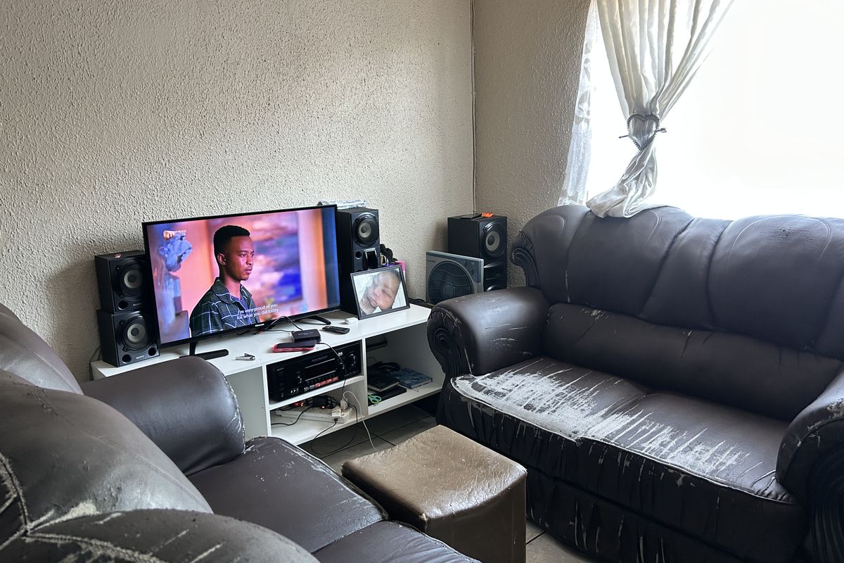 A living room area featuring tiled flooring and a window, currently utilized as a lounge space.
