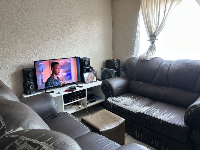 A living room area featuring tiled flooring and a window, currently utilized as a lounge space.