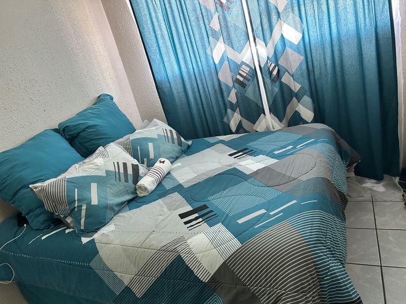 A bedroom featuring tiled flooring and a window covered by curtains.