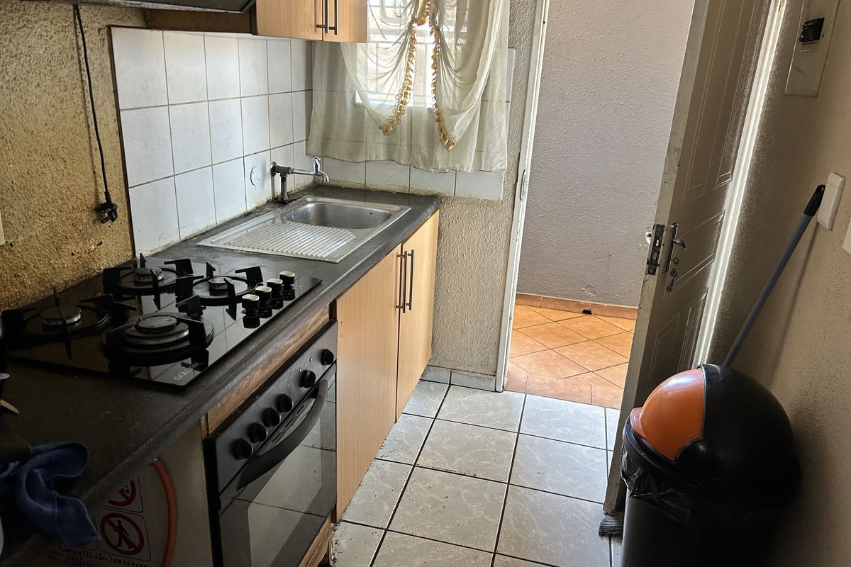 Compact kitchen featuring a gas hob, built-in oven, and tiled splashback, with direct access to an outdoor patio area.