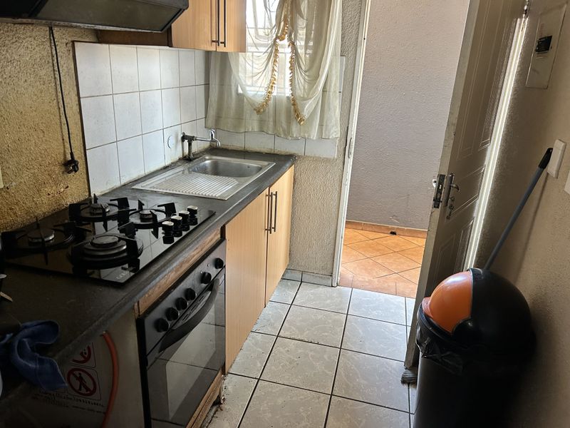 Compact kitchen featuring a gas hob, built-in oven, and tiled splashback, with direct access to an outdoor patio area.