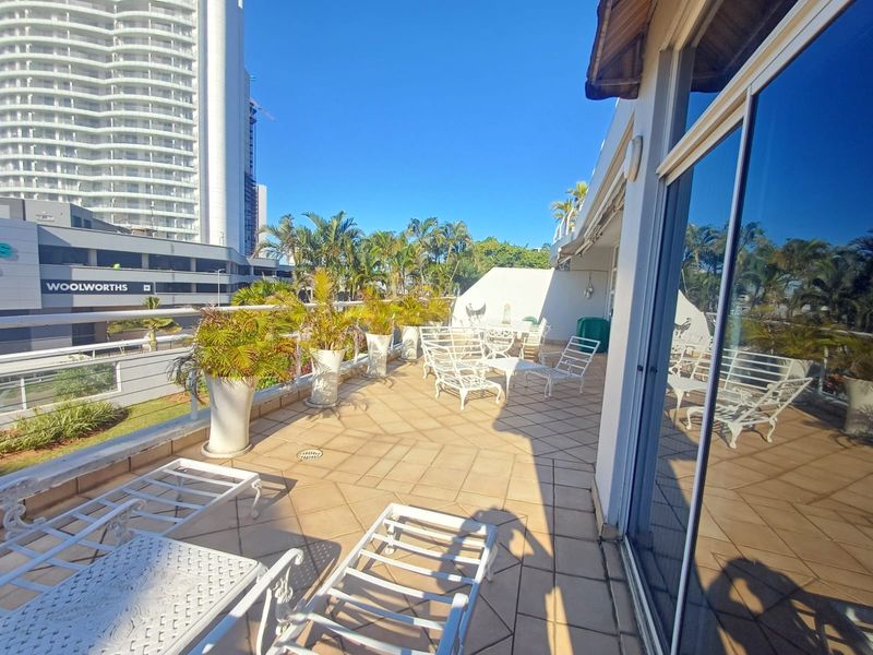 Spacious outdoor balcony featuring tiled flooring, metal balustrades, and large sliding glass doors, offering an open-air space for relaxation.