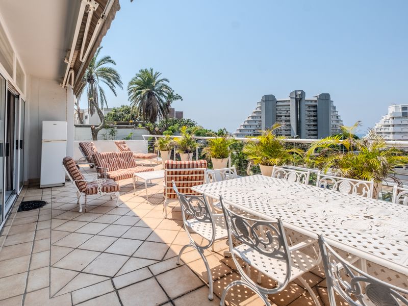 Spacious balcony featuring tiled flooring, a retractable awning, and sliding glass door access, offering an ideal outdoor space for relaxation and entertaining.