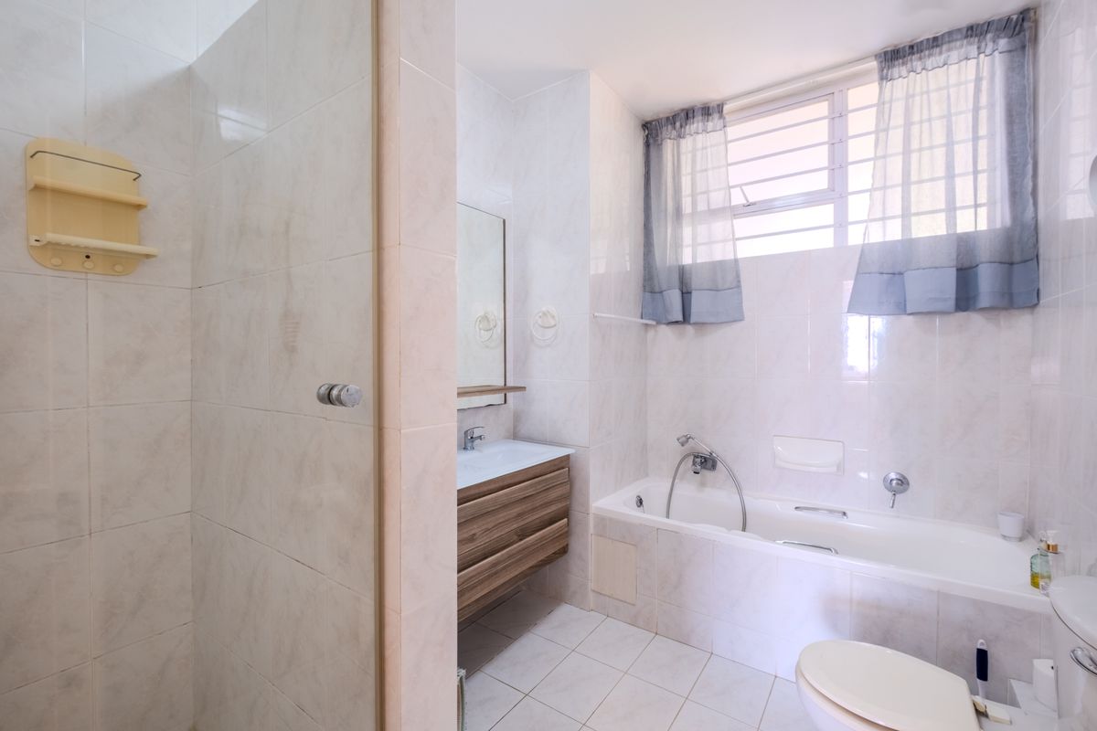 A functional bathroom featuring a built-in vanity, a bathtub, a separate shower enclosure, and tiled finishes throughout.