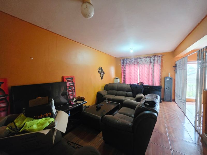 A living room area featuring tiled flooring and access to an outdoor space through a security gate and sliding door.