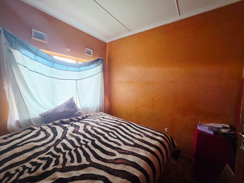 A bedroom featuring parquet flooring and wall-mounted air vents, currently requiring cosmetic updates to the wall finishes.