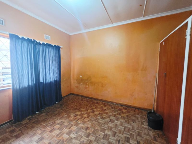 A bedroom featuring parquet flooring and a built-in cupboard, requiring cosmetic updates to the walls to improve the overall condition.