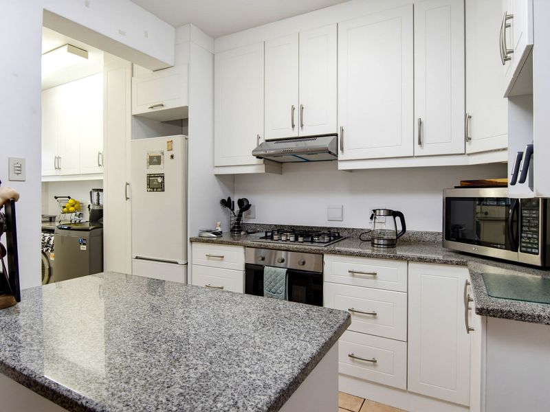Modern kitchen featuring granite countertops, built-in cabinetry, gas hob, and an integrated oven, with an adjacent scullery area for added convenience.