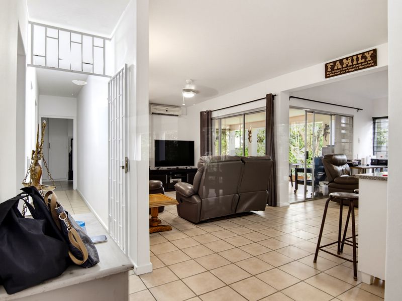 Open-plan living area featuring tiled flooring, a breakfast counter, and large sliding glass doors providing access to the outdoor space.