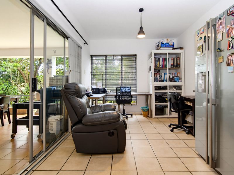 Open plan living area featuring tiled flooring, pendant lighting, and large sliding glass doors providing access to an outdoor patio space.