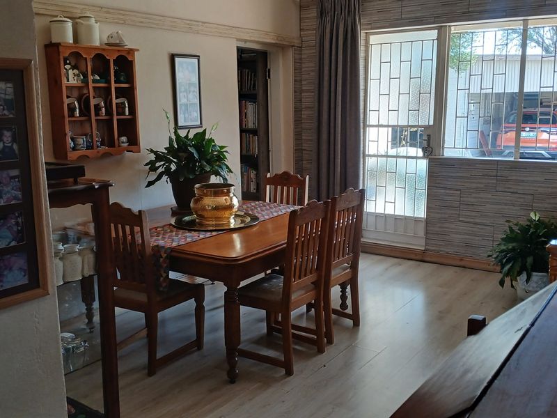 A dining room featuring laminate flooring, built-in shelving, and a security gate leading to the exterior.