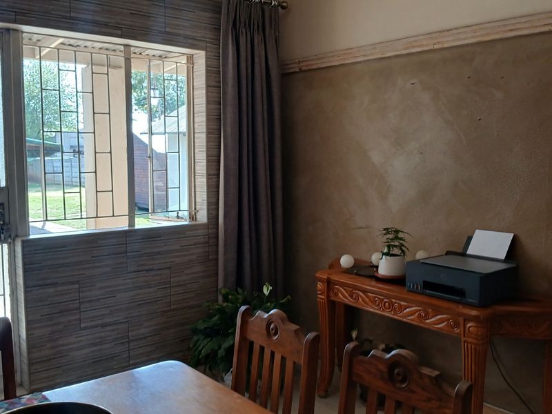 Living area featuring a security gate, burglar bars, and an unfinished plaster wall requiring final finishing or painting.