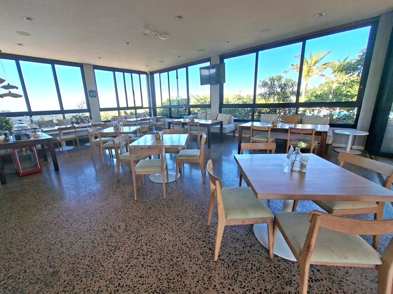Spacious open-plan dining area featuring polished terrazzo flooring and expansive floor-to-ceiling windows offering abundant natural light and scenic views.