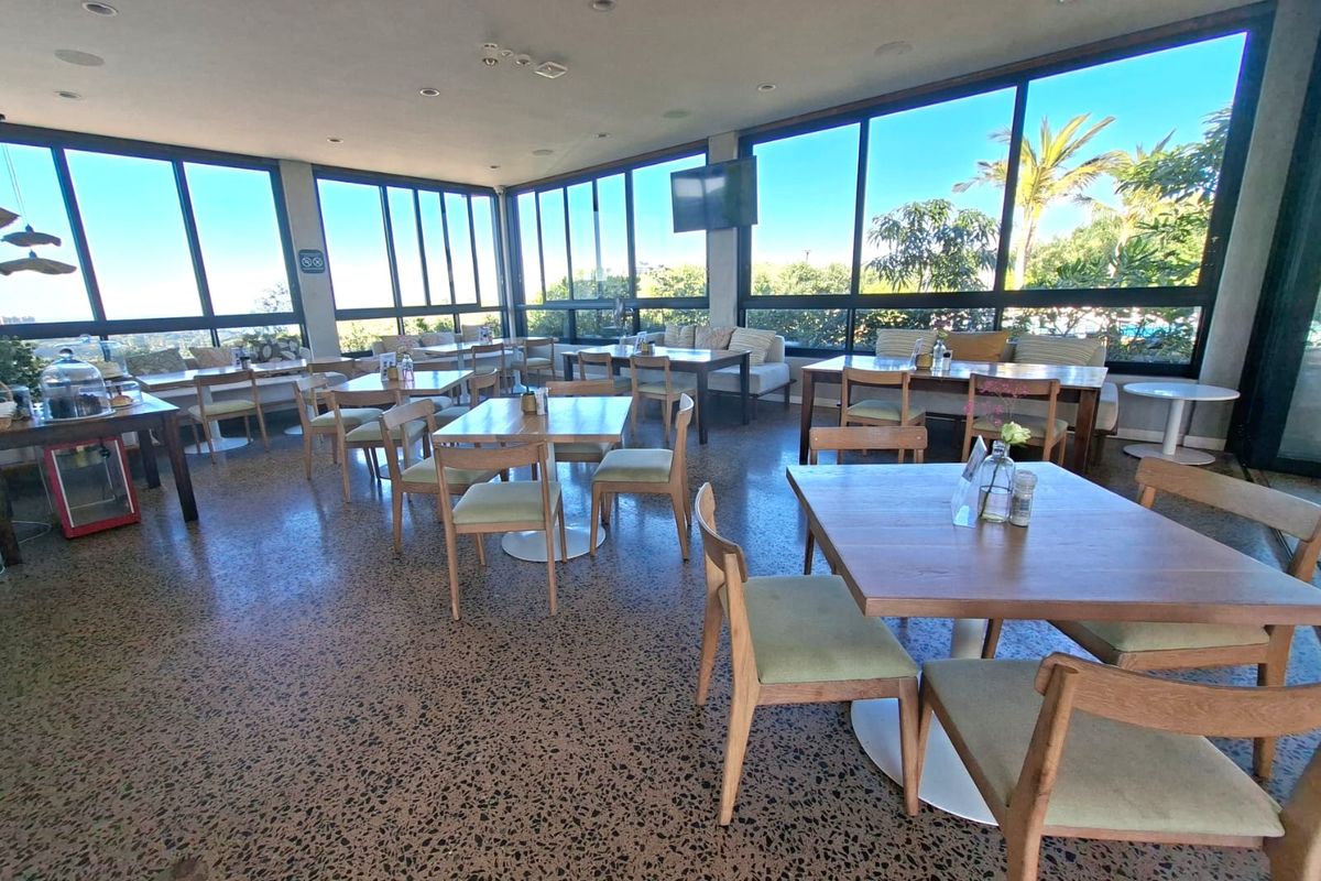Spacious open-plan dining area featuring polished terrazzo flooring and expansive floor-to-ceiling windows offering abundant natural light and scenic views.