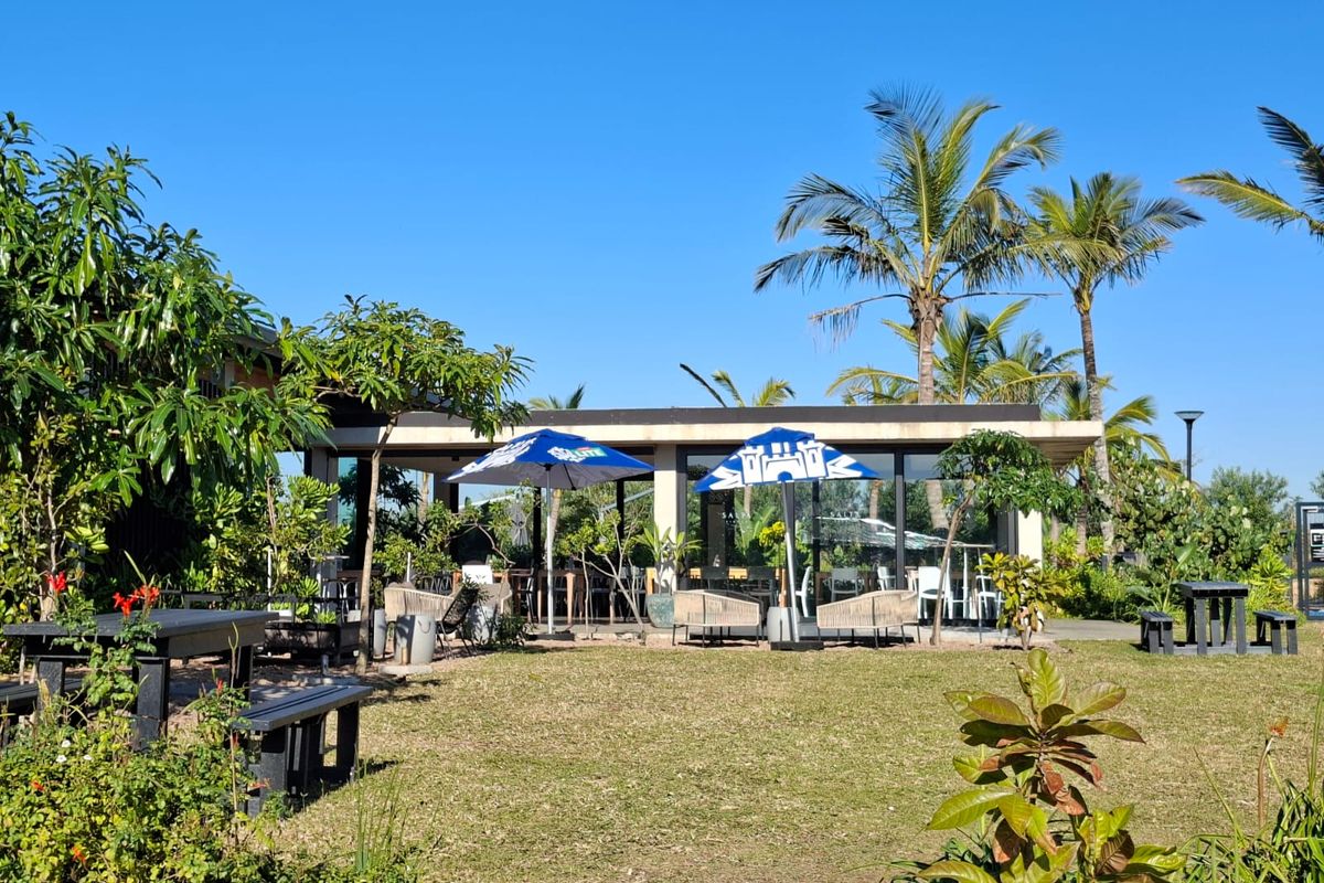 A well-maintained garden area featuring mature palm trees, a paved patio space, and established landscaping, providing a pleasant outdoor setting.