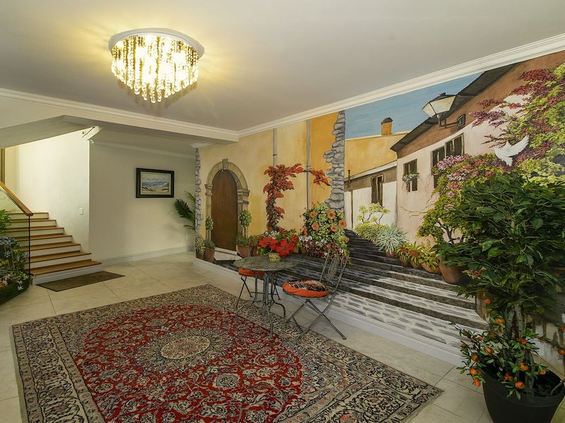 Spacious entrance hall featuring tiled flooring, a grand crystal chandelier, and a staircase leading to the upper level.