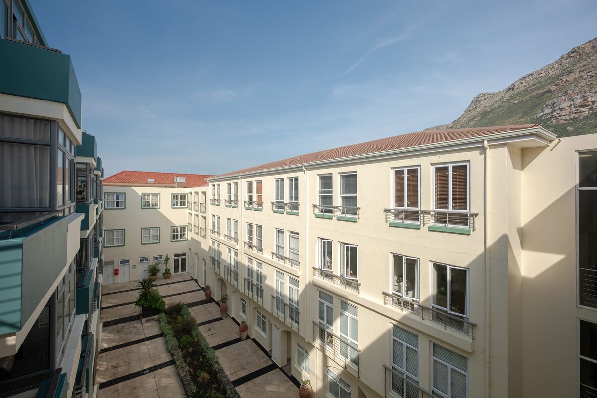 A view of the apartment complex courtyard featuring a paved area, landscaped garden beds, and multi-story building facades with balcony railings.