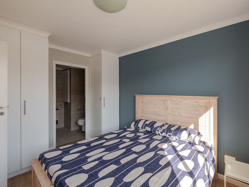 A well-maintained bedroom featuring built-in cupboards, laminate flooring, and an en-suite bathroom access.