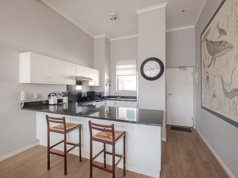 A functional kitchen featuring granite countertops, white cabinetry, and laminate flooring, designed with a breakfast bar for casual dining.