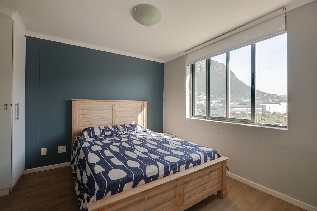 A well-maintained bedroom featuring laminate flooring, a built-in wardrobe, and a large window with mountain views.