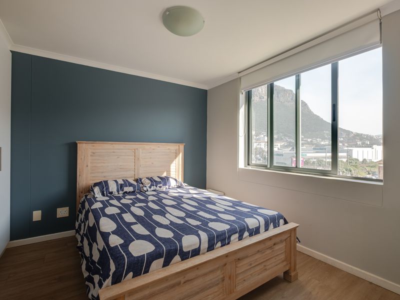 A well-maintained bedroom featuring laminate flooring, a built-in wardrobe, and a large window with mountain views.