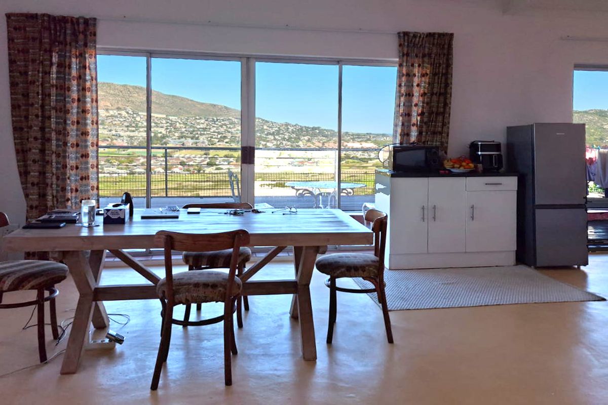 Open plan living and dining area featuring polished concrete floors and large sliding glass doors that open to a scenic outdoor balcony.