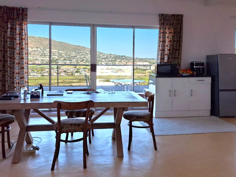 Open plan living and dining area featuring polished concrete floors and large sliding glass doors that open to a scenic outdoor balcony.