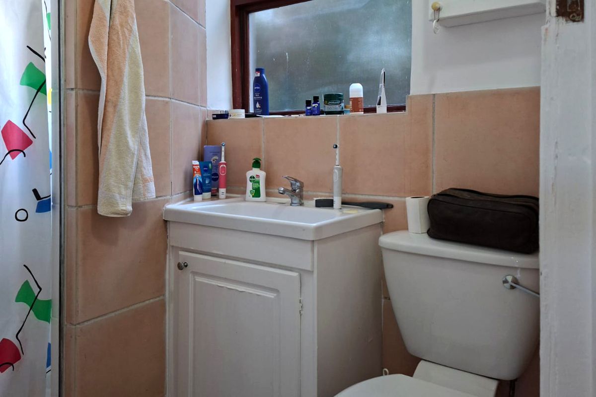 A compact bathroom featuring a vanity cabinet with basin, toilet, and shower enclosure with tiled walls.