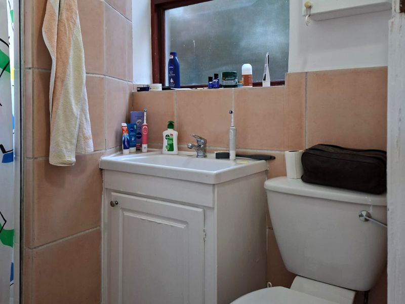 A compact bathroom featuring a vanity cabinet with basin, toilet, and shower enclosure with tiled walls.