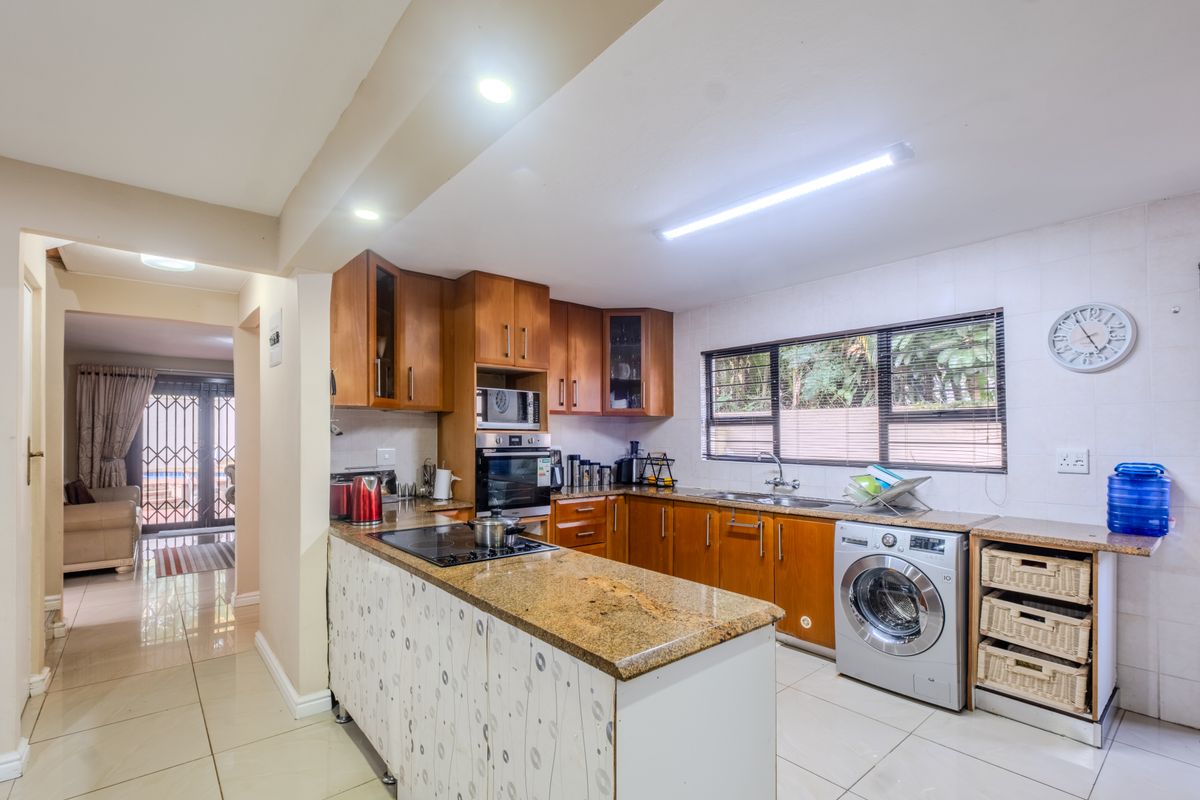 Functional kitchen featuring granite countertops, wooden cabinetry, built-in oven, and integrated laundry space, with direct access to the adjacent living area.