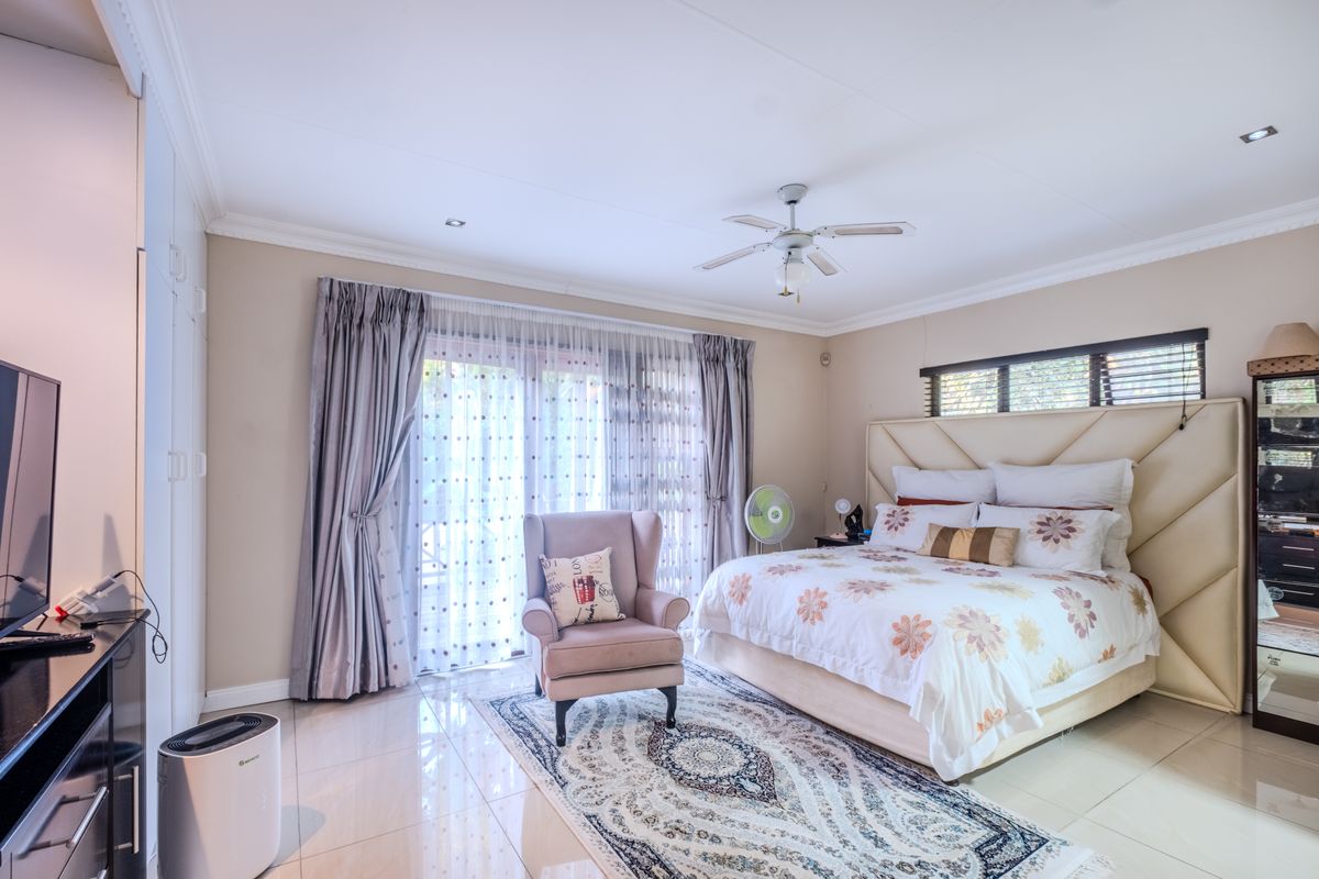 Spacious bedroom featuring tiled flooring, built-in cupboards, a ceiling fan, and a sliding glass door providing access to the outdoors.
