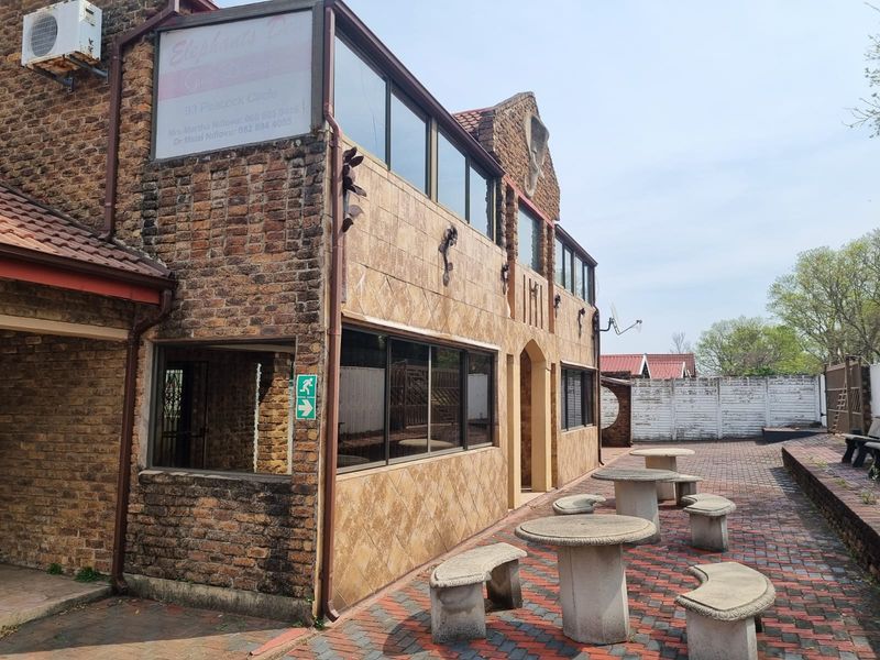 Rear exterior view of a multi-story face brick building featuring tiled wall accents, aluminium windows, and a paved courtyard area.
