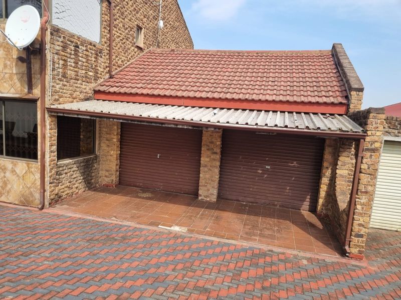 A double garage featuring roller doors, a tiled driveway, and a combination of brick and tiled roofing.