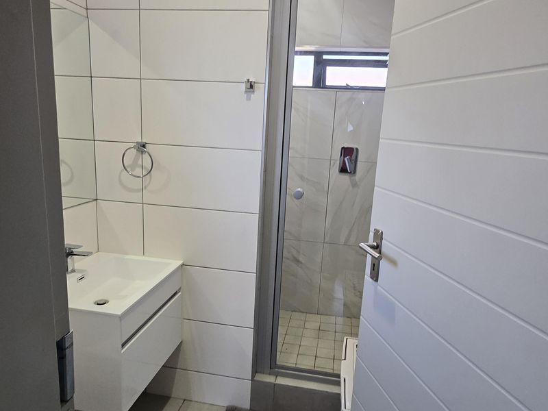 A modern, compact bathroom featuring a wall-mounted vanity, tiled finishes, and a separate shower enclosure.