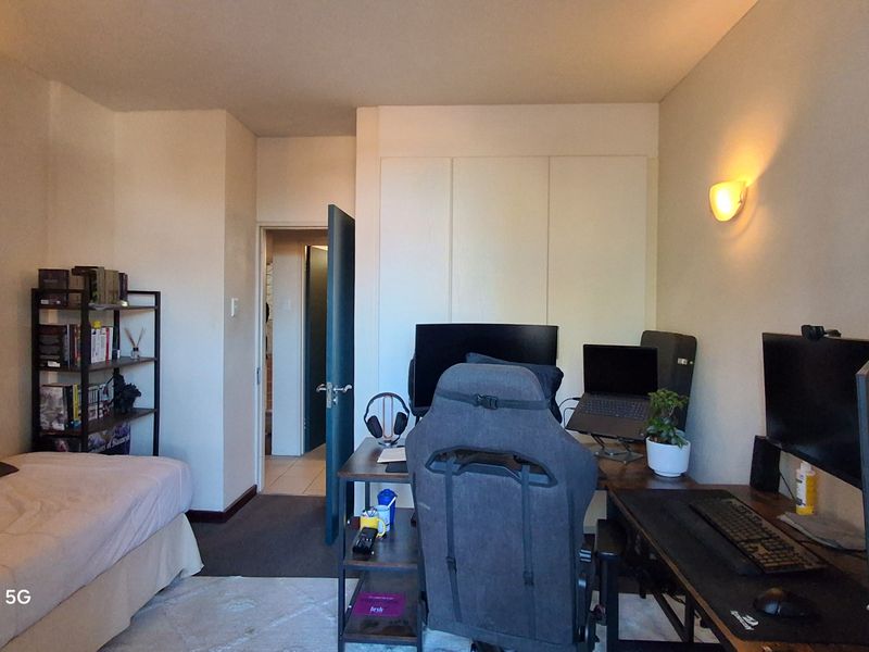 A functional bedroom featuring built-in cupboards and a wall-mounted light fixture, providing a practical layout for living and workspace needs.