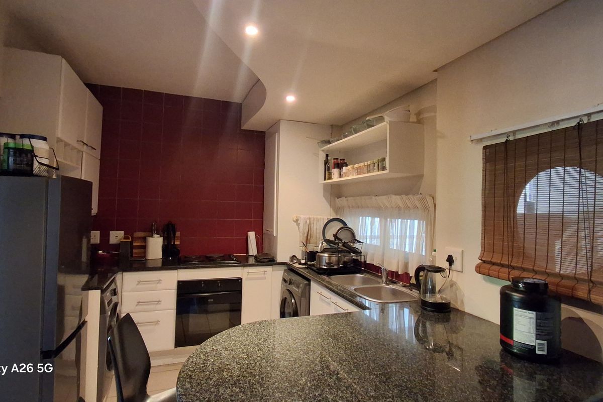 Functional kitchen featuring granite countertops, built-in cabinetry, an electric oven, and a tiled backsplash with a breakfast bar area.
