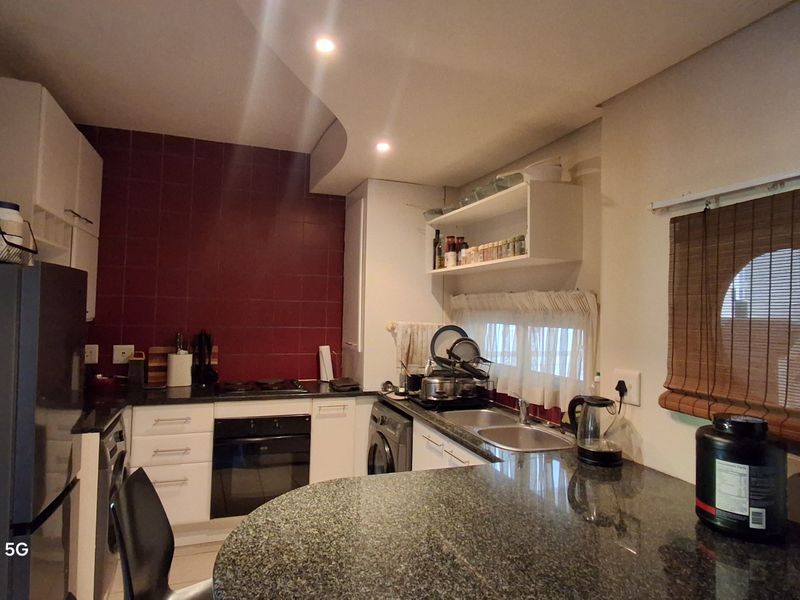 Functional kitchen featuring granite countertops, built-in cabinetry, an electric oven, and a tiled backsplash with a breakfast bar area.