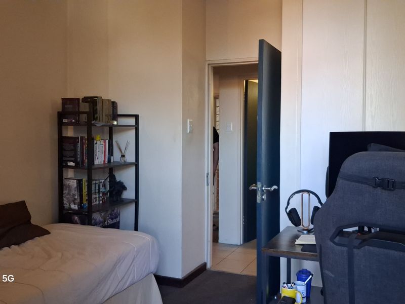 A functional bedroom featuring built-in cupboards and direct access to the hallway, offering a practical layout for a compact living space.