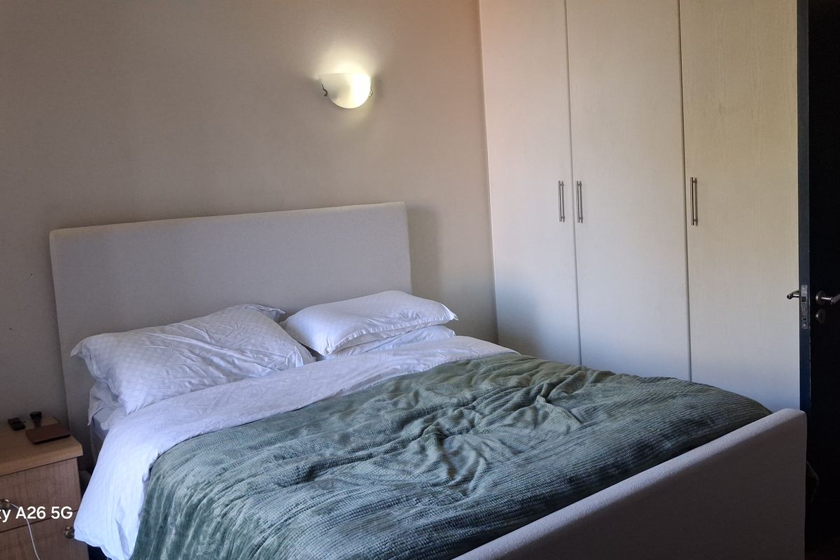 A bedroom featuring built-in cupboards and wall-mounted lighting, providing functional storage and ambient illumination.