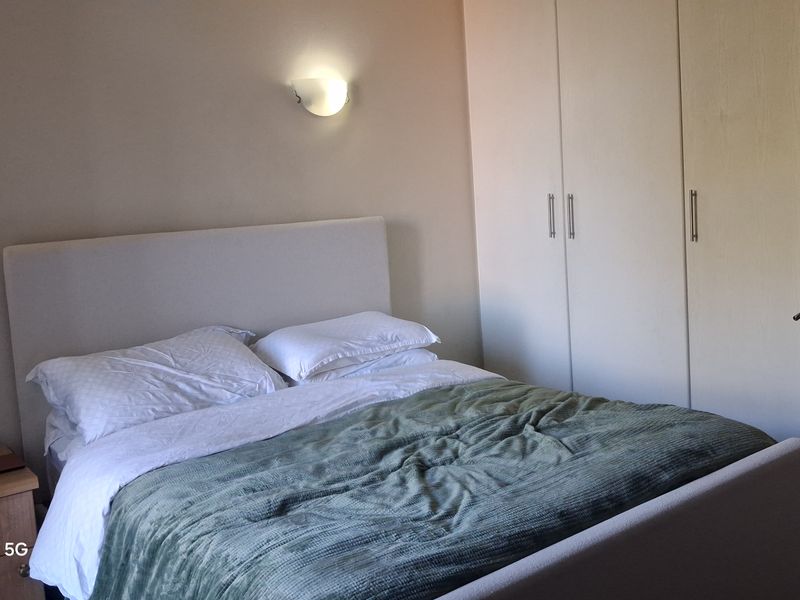 A bedroom featuring built-in cupboards and wall-mounted lighting, providing functional storage and ambient illumination.