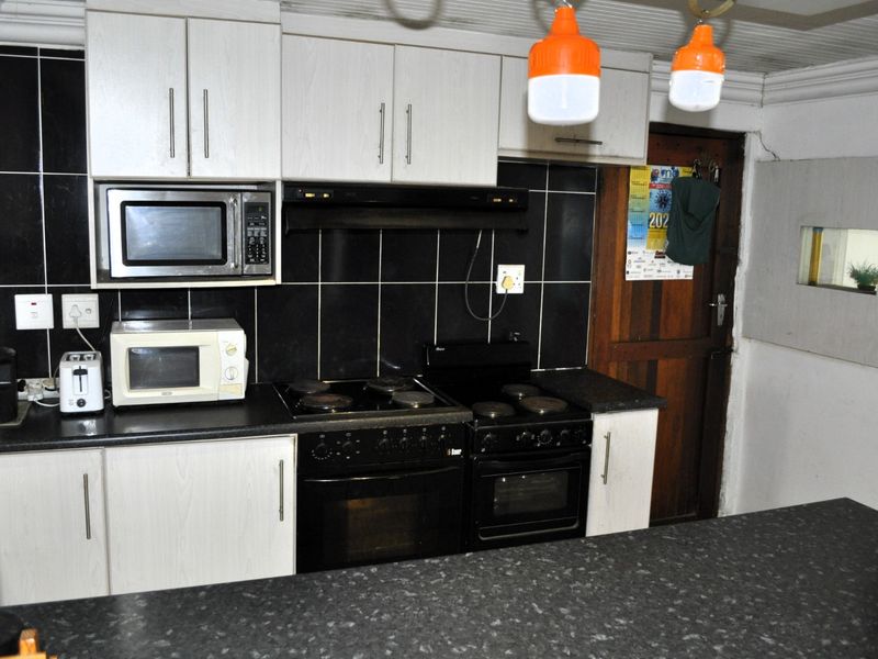 Functional kitchen featuring black tiled backsplash, laminate countertops, built-in cabinetry, and integrated cooking appliances.