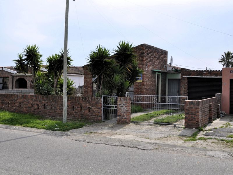 Front view of a face brick house featuring a gated entrance, paved driveway, and attached garage in a residential street setting.
