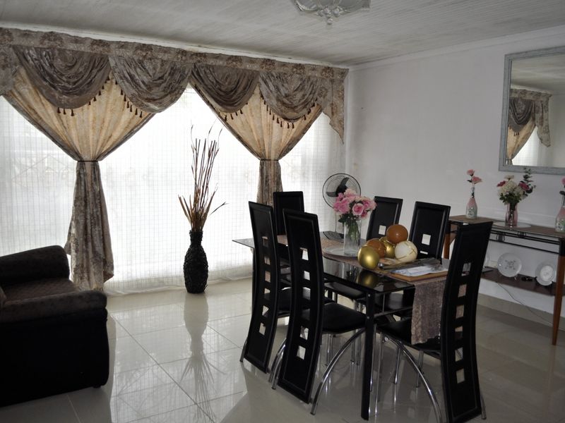 A dining room featuring polished tiled flooring and a tongue and groove ceiling, providing a functional space for family meals.