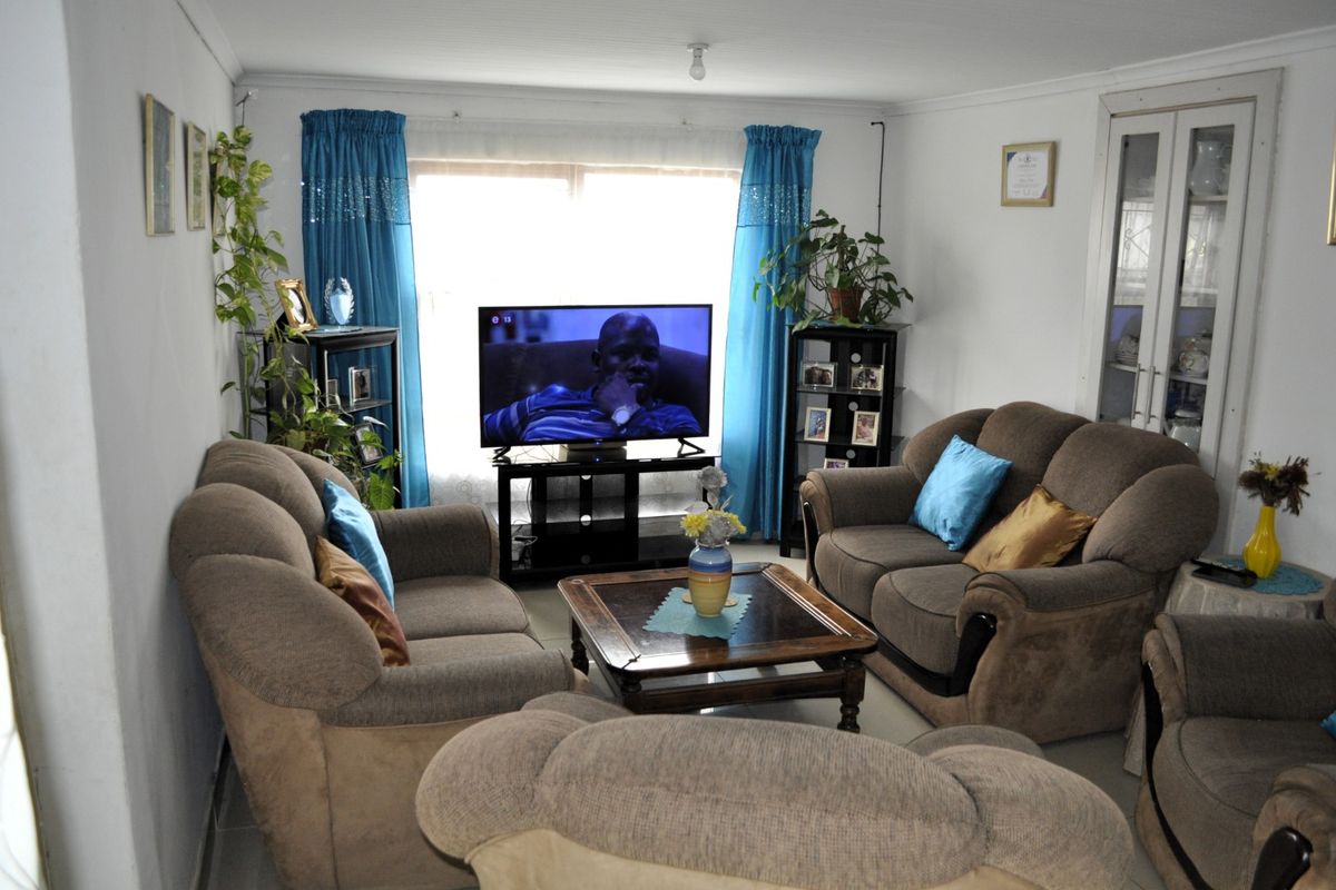 A comfortable living room featuring tiled flooring, coved ceilings, and a built-in display cabinet, offering a functional and well-maintained space.