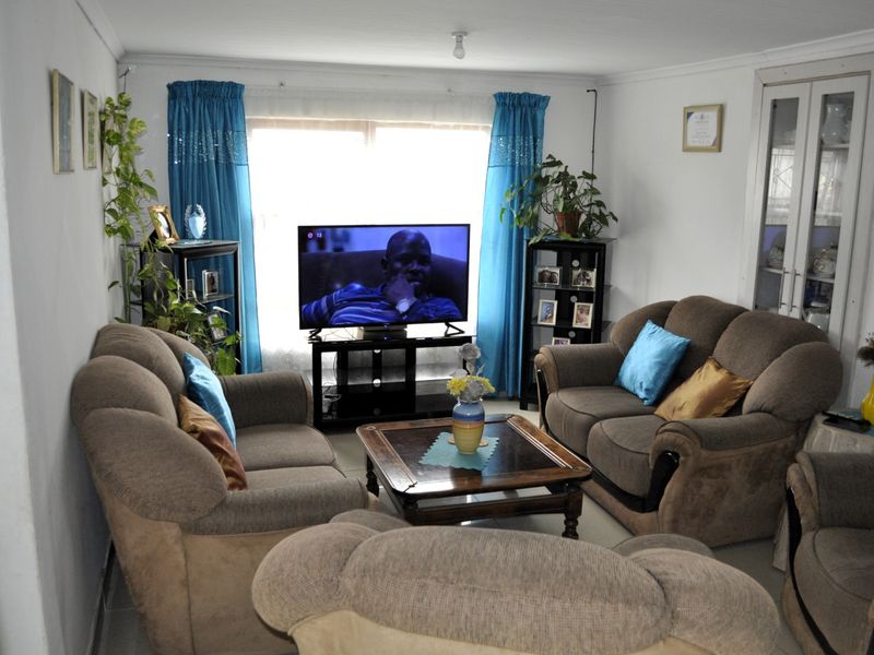A comfortable living room featuring tiled flooring, coved ceilings, and a built-in display cabinet, offering a functional and well-maintained space.